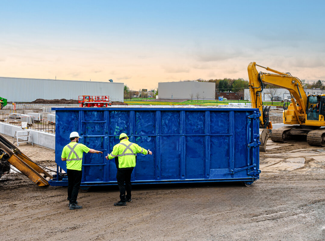 66a28bedb780beb776b22f00 Two workers unloading an Enviro Connexions Roll Off container on a construction site