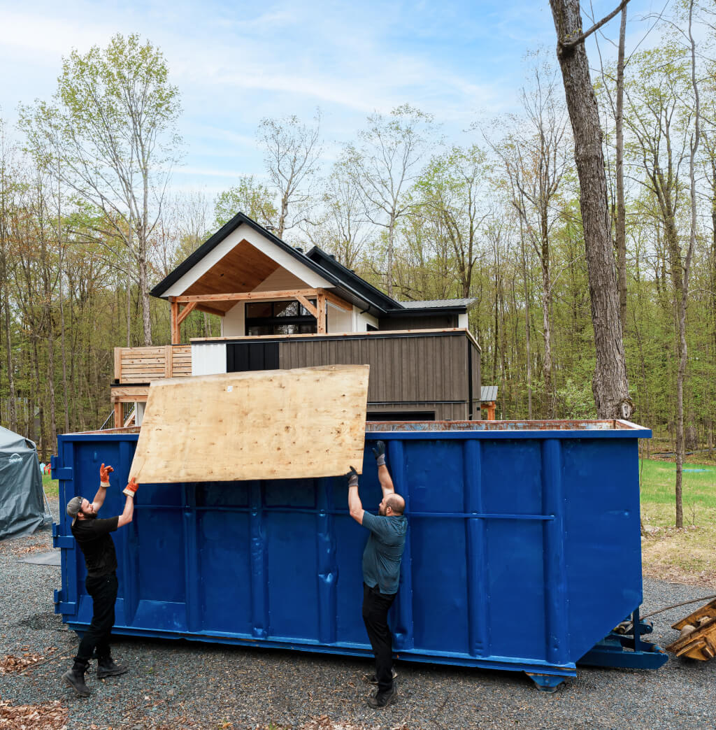 66a295a69e264a6a31fdc2c6 Two men putting waste in a blue Enviro Connexions residential roll off dumpster container